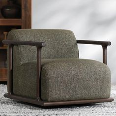 a green chair sitting on top of a rug next to a wooden book shelf and cabinet