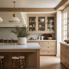 a large kitchen with wooden cabinets and white counter tops, along with two stools