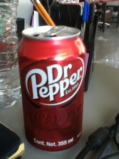 a can of soda sitting on top of a table next to a pair of scissors