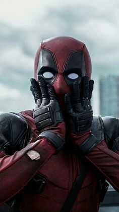 the deadpool character is holding his hands up to his face and looking at something