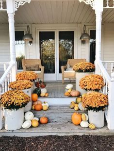 pumpkins and gourds are arranged on the porch