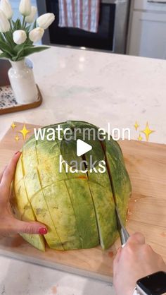 someone cutting up a watermelon on top of a wooden cutting board