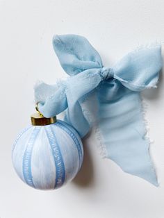 an ornament with a blue ribbon tied around it on a white wall next to a torn piece of paper