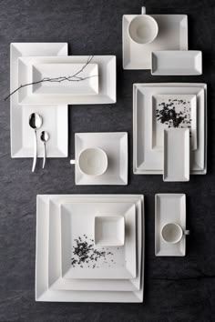 white plates and dishes are arranged on a black surface