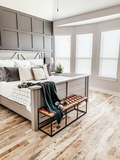 a bed sitting on top of a wooden floor in a bedroom next to two windows