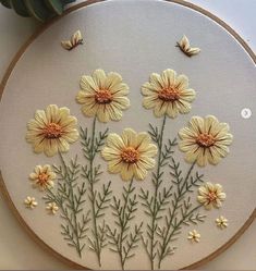 a close up of a embroidery on a white surface with yellow flowers and green leaves