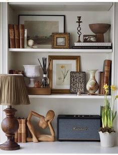 a shelf filled with books and pictures next to a lamp