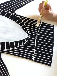 a person cutting fabric with scissors on top of a piece of cloth that has been cut into strips