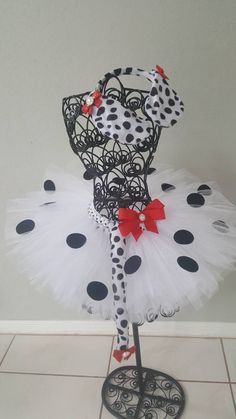 a black and white polka dot tutu with red bow on it's head