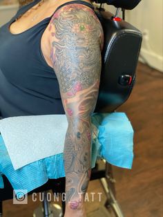 a woman sitting in a chair with tattoos on her arm