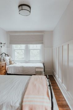 two beds in a room with white walls and wood floors