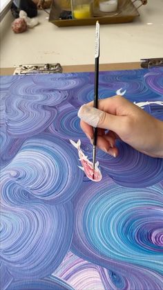 a person holding a paintbrush in their left hand and painting on a piece of paper