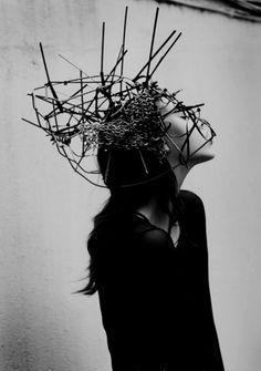 black and white photograph of a woman with sticks in her hair wearing a crown of twigs