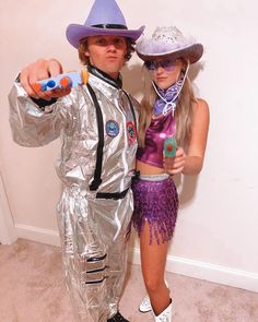 a man and woman dressed up in tinfoil for halloween costumes, one pointing at the camera