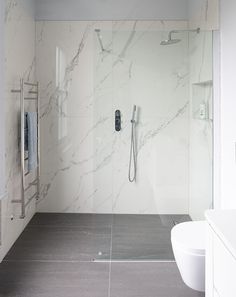 a white bathroom with marble walls and floor