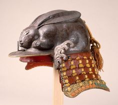 a metal sculpture of a rabbit laying on top of a wooden stick with a hat on it's head