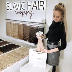 a woman standing in front of a table holding a bag with some hair on it