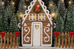 a gingerbread house decorated for christmas with lights and decorations on the front door, surrounded by evergreen trees