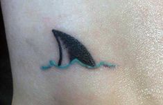 a small shark tattoo on the ankle