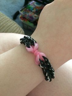 a person wearing a pink and black bracelet on their left arm with braiding around the wrist