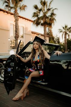 a woman sitting on the hood of a car with her graduation cap over her head