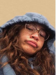 a woman with long hair wearing glasses and a blue hoodie looking at the camera