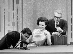 two men and a woman looking at something on a table