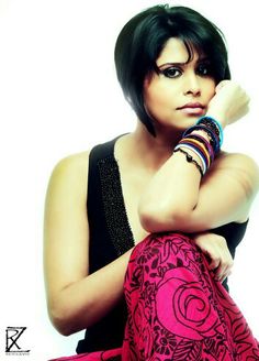 a woman sitting on the floor with her hand on her knee and wearing bracelets