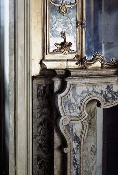 an ornate gold and white clock on top of a marble fireplace mantel in a room