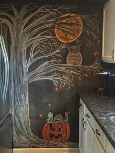 a kitchen painted with an owl and pumpkin theme on the wall, next to a refrigerator