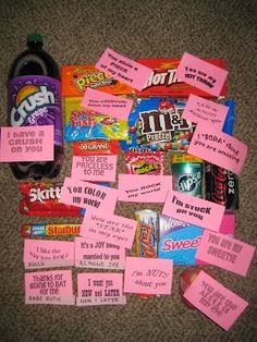 a pile of candy with pink stickers on them next to a bottle of soda