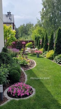 a garden with lots of flowers and plants in it's center, next to a house