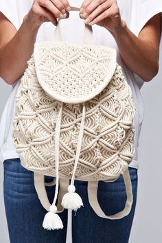 a woman wearing a white backpack with tassels on the front and back sides