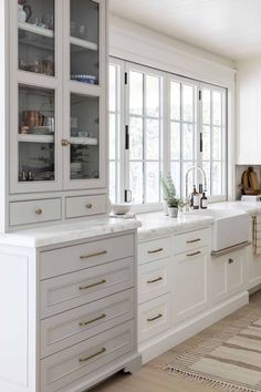 a large kitchen with white cabinets and marble counter tops