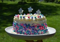 a birthday cake with white frosting and colorful sprinkles on a plate