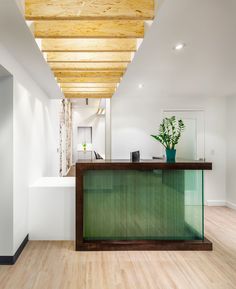 an empty reception area with wood floors and white walls, along with a green counter