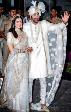 a man and woman dressed in white posing for the camera