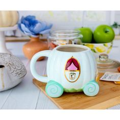 a coffee mug with an image of a princess carriage on it sitting on a cutting board