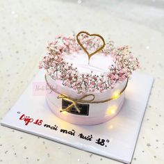 a heart shaped cake on top of a white plate with pink flowers and lights around it