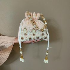 This Pearl and Zirconia and Sequin studded Peach Potli is a beautifully handcrafted Indian Batwa Bag, perfect for adding a touch of traditional elegance to any occasion. The bag features a stunning peach base adorned with intricate pearl embroidery, creating a luxurious and festive appeal. The shimmering sequins add a glamorous flair, making it an ideal accessory for brides or wedding guests. ✅ How To Order Please select your color in option. ✅ SPECIFICATIONS: ⦿  Available in 3 colors : Hot pink, Baby blue, Peach  ⦿ Dimension: Length 9", Width 9" ⦿ Item Type: Indian Potli Bag ⦿ Material: Fabric, Sequins, Zardosi, Etc. ⦿ Gender: Women ✅ FEATURES: ⦿ Made using beads and sequins and rhinestones on silk fabric ⦿ Ethnic and contemporary ⦿ Has a drawstring closure ⦿ Add a touch of glamour ⦿ Plea Return Gifts Indian, Clutch Purse Wedding, Bride Clutch, Purse For Wedding, Purse Wedding, Pearl Embroidery, Potli Bag, Indian Gifts, Simi Valley