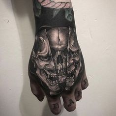 a hand with a skull and rose tattoo on it