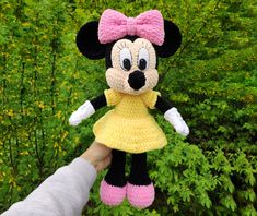 a crocheted minnie mouse doll is being held by a person's hand