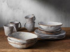 a table topped with lots of white dishes next to cups and saucers on top of a wooden table