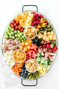 a platter filled with different types of fruits and veggies on top of a white table