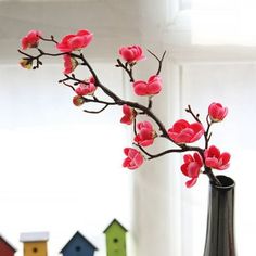 a vase filled with pink flowers sitting on top of a table next to bird houses