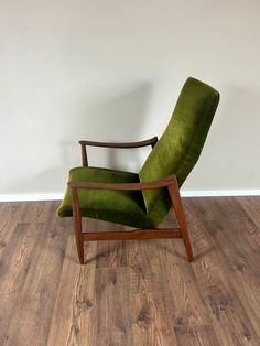 a green chair sitting on top of a hard wood floor next to a white wall