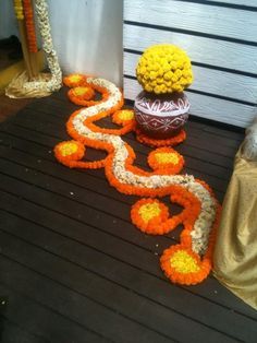 an arrangement of flowers and decorations on a wooden floor in front of a building with white walls