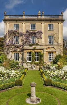 a large building with lots of flowers in front of it and a fountain in the middle of the yard