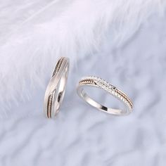 two wedding rings sitting next to each other on top of a white fur covered surface