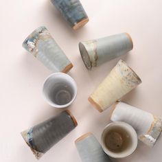 several cups and saucers are arranged on a table top, with one cup in the middle